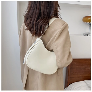 Close-up of a cream-colored leather hobo shoulder bag styled with a striped blazer