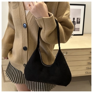 Close-up of black matte hobo bag on a model wearing a cardigan and plaid skirt