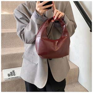 Detail of a dark red hobo bag with vintage checkered texture held by a model