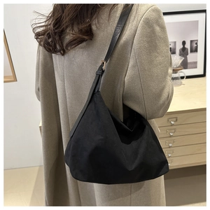 Detail view of large black tote bag on shoulder with vintage suede finish and metal buckle