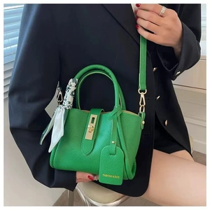 Close-up of green lychee pattern bucket bag with gold lock and decorative silk scarf