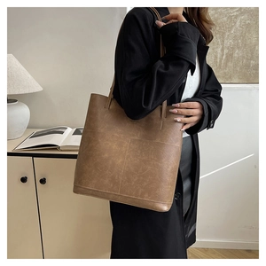 Macro detail of brown leather tote bag showing vintage texture and precise stitching