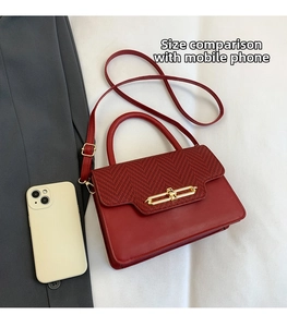 Detail view of red leather and herringbone fabric handbag showing phone size comparison