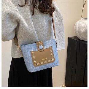 Detail showing blue wool texture and brown leather front pocket with bead accents