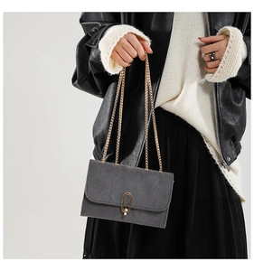 Détail du sac bandoulière en daim gris avec fermoir rotatif doré et fine bandoulière
