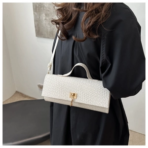 Detail of white rectangle handbag showing faux crocodile texture and gold twist lock
