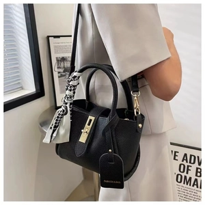 Detail of black lychee grain leather bucket bag with golden twist lock and houndstooth scarf
