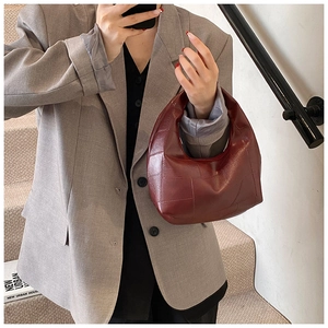 Detail of dark red pleated cloud bag showing quilted texture and underarm wear style