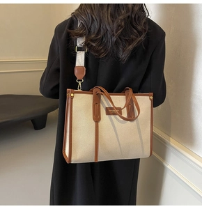 Détail d'un cabas en toile beige avec bordure en cuir marron et écusson logo élégant
