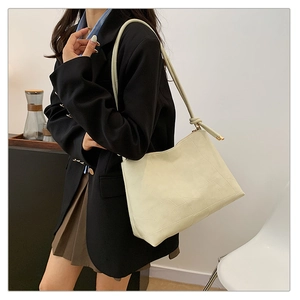 Close-up of cream faux leather shoulder bag featuring geometric patchwork texture