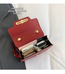 Detail view of red leather crossbody bag showing spacious interior with personal items