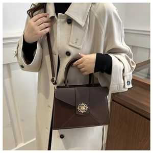Detail shot of a dark brown crossbody bag worn with a chic autumn trench coat