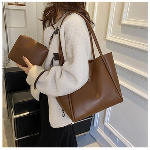 Brown leather tote bag and clutch set styled in a cozy minimalist interior setting