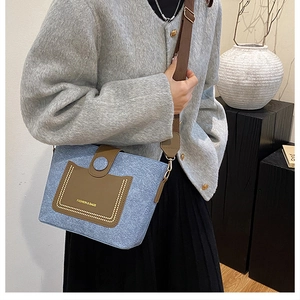Detail of blue tweed crossbody bag with brown leather flap and golden fashion logo