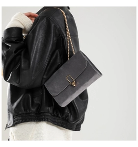 Détail du sac bandoulière en daim gris foncé avec fermoir doré et chaîne élégante