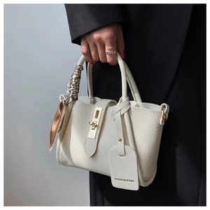 Detail of white lychee leather bucket bag with gold clasp and decorative silk scarf