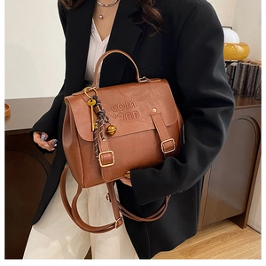 Detail of vintage brown leather backpack with metal buckles and decorative key pendant