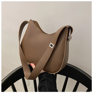 Detail of a minimalist dark brown crescent moon underarm bag with wide shoulder strap