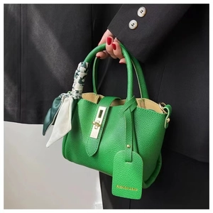 Detail of green lychee leather bucket bag with gold clasp and decorative silk scarf