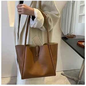 Detail of a brown PU leather tote bag showing the buckle closure and matte texture