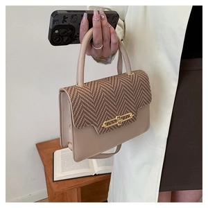 Close-up of beige leather and brown herringbone fabric bag with gold clasp detail