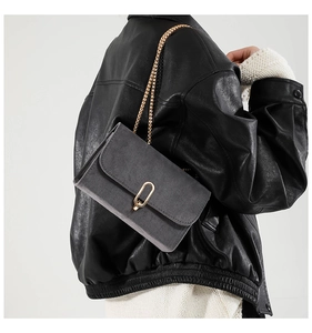 Détail du sac carré en daim gris avec bandoulière chaîne dorée et fermoir en métal