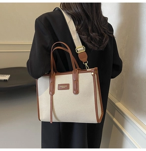 Détail d'un cabas en toile avec garniture en cuir marron et large bandoulière en tissu amovible