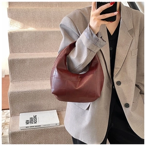 Burgundy pleated hobo bag with grid stitching texture shown on a female model