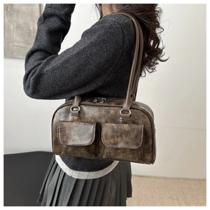 Dettaglio borsa a tracolla marrone vintage con doppie tasche frontali e pelle lucida