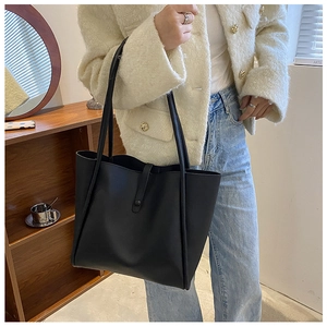 Detail of black leather tote bag showing the magnetic snap closure and large capacity