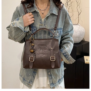 Detail of dark brown retro leather backpack with metal buckles and letter embossing