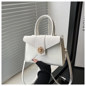 Detail of white leather handbag with golden petal clasp and elegant top handles