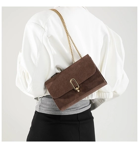 Brown suede shoulder bag featuring a gold U-shaped buckle and fine chain strap
