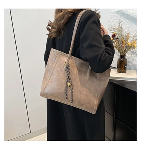 Detail of mocha brown tote bag featuring decorative striped drawstring and gold bell accent