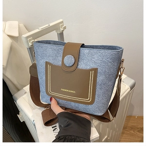 Detail of denim texture shoulder bag with golden studs and wide brown fabric strap