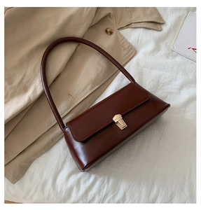 Détail d'un sac baguette vintage en cuir marron foncé avec fermoir doré poli