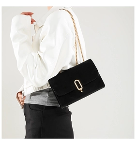 Détail d'un chic sac à bandoulière noir mat avec fermoir doré et chaîne en métal élégante