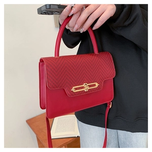 Detail of red leather handbag featuring herringbone fabric flap and gold metal lock