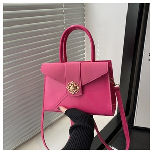 Detail of rose pink handbag with golden floral metal buckle and envelope flap design