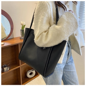 Detail view of large black leather tote bag showing side stitching and shoulder strap