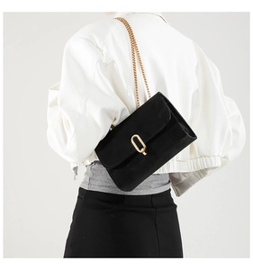 Detail view of black frosted shoulder bag with gold chain and oval twist lock