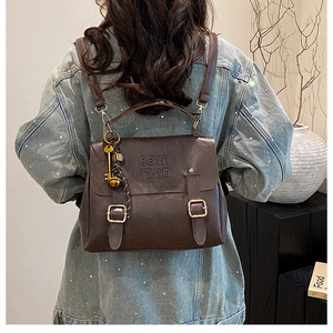 Detail view of vintage dark brown leather backpack with coin embossing and key charm