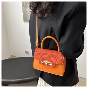Close-up of orange textured small square bag with golden twist lock and top handle