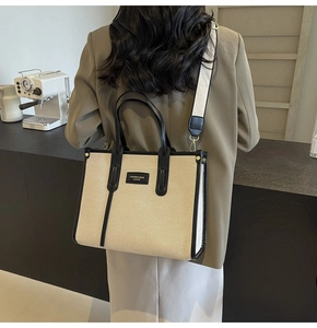 Grand sac cabas en toile avec bordure en cuir noir porté par un mannequin de mode