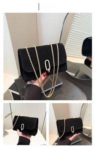 Detail of black suede rectangular crossbody bag with golden chain and oval metal clasp