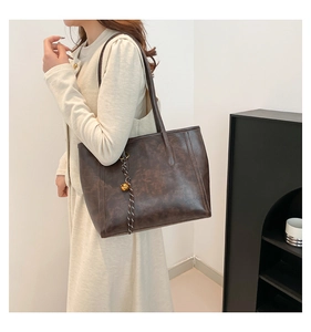 Close-up of vintage brown tote bag with woven charm and large capacity for daily commute
