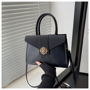 Detailed view of the matte leather texture and elegant gold floral buckle on a black bag