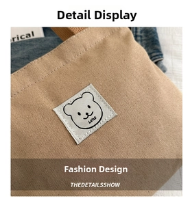 Close-up of khaki canvas makeup bag featuring a cute bear patch and durable textured fabric