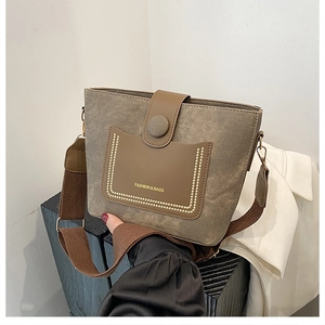 Detail of grey canvas and brown leather stitching with wide strap and gold rivets