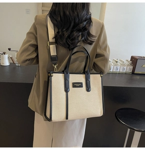 Détail du sac cabas en toile avec bordures en cuir noir et large bandoulière portée